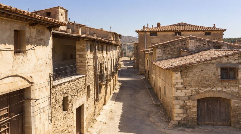 La calle La Barca, seca, vista desde arriba: baja recta entre casas de mampostería con balcones y un portal de arco, sin nadie en primer plano.