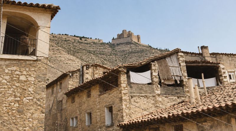 A la izquierda, la casa de Fustigueres con una galería de arco; a la derecha, buhardillas abiertas con ropa tendida, y sobre la ladera abancalada, el castillo.