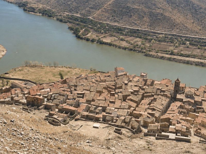 Caserío apretado visto desde el cerro, con el campanario a la derecha, el río ancho y llano a la izquierda y el campo de fútbol entre los dos ríos.